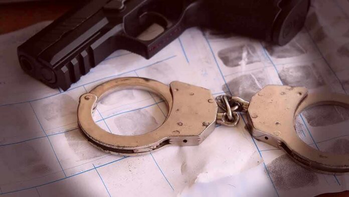 Handcuffs on fingerprint sheets beside a handgun