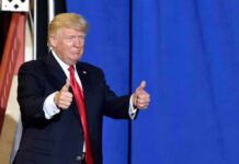 Trump’s Arch Goes Military? Donald Trump giving two thumbs up in front of a blue curtain
