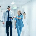 Major Hospital’s Controversial Gender Practices Busted Doctor and nurse walking in a hospital corridor reviewing a tablet