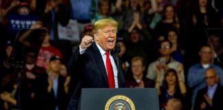 man speaking at a podium during a rally