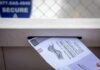 Election Rule Freeze Sparks Impeach Push Mail-in ballot being inserted into a secure drop box slot