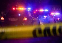 Rest-Stop Bloodbath Stuns I-80 Police cars with flashing lights behind yellow caution tape at night