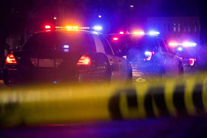 shutterstock_1349511497 Police cars with flashing lights behind yellow caution tape at night