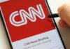 CNN logo on a smartphone screen with a hand holding a stylus