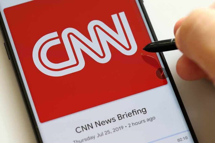 CNN logo on a smartphone screen with a hand holding a stylus