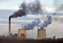 Industrial power plant with smokestack and cooling towers emitting smoke