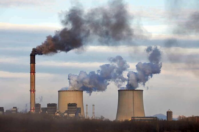Industrial power plant with smokestack and cooling towers emitting smoke