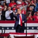 Massive Dallas Showdown Electrifies 2026 man in suit points from a stage at a political rally