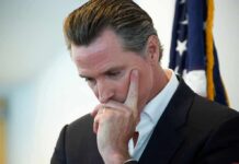 Newsom Claims Slammed By His Own Numbers man in suit touching his face thoughtfully