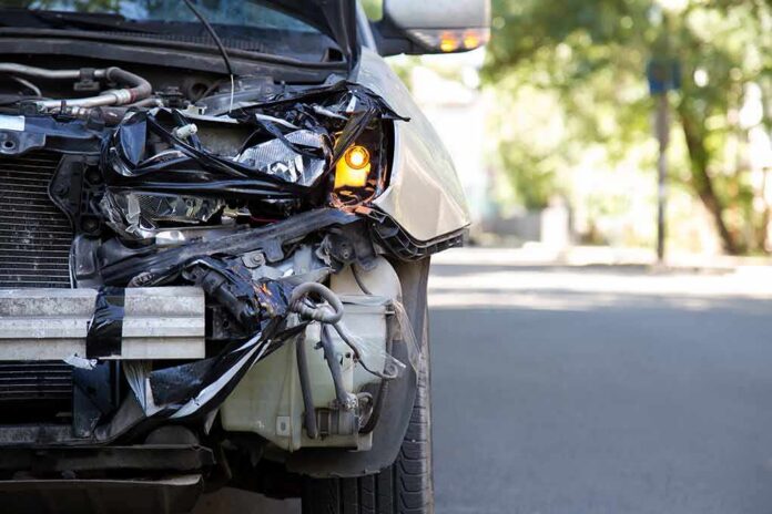Front of a car with severe collision damage and exposed headlight