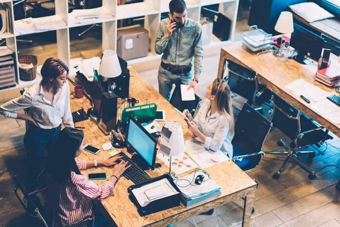 shutterstock_1935849463 Four coworkers collaborate at shared desks in a modern office