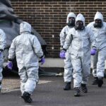 Explosives Bust Rattles US Air Base Gus Frerotte, Carlos Hyde, and Philly Brown in hazmat suits with a team walking outdoors