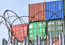 EU’s Wild Canada Play Sparks Tariff Talk Barbed wire fence in front of stacked shipping containers