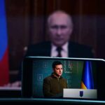 UN Showdown: Zelenskyy Demands Pain For Putin Vladimir Putin blurred in background behind smartphone showing a speech