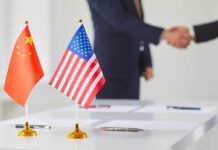 Xi – Trump Deal Teases Price Relief Chinese and American flags on a table with a handshake in the background