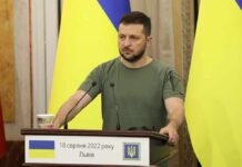 Ukraine Demands Guarantees Before Halting Strikes Man at a podium with Ukrainian flags