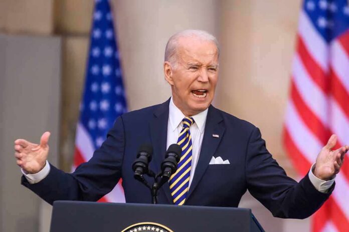Joe Biden speaking at a podium with U.S. flags in the background
