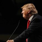 Trump Torches Globalism at the UN Donald Trump speaking at a podium in profile against a dark background