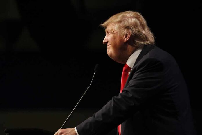 shutterstock_353100986 Donald Trump speaking at a podium in profile against a dark background