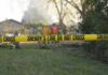 Bat-Swinging Fugitive Terrifies Quiet Town Yellow police tape marking a restricted area at a fire scene with firefighters in the background