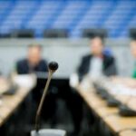 Caraun Reid at a conference table with a microphone in focus