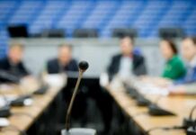 Caraun Reid at a conference table with a microphone in focus
