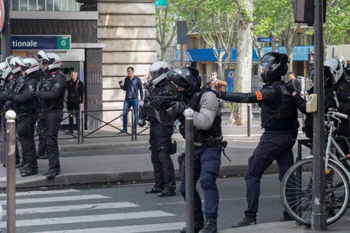 shutterstock_1392139244 Riot police in helmets line a city street during an operation
