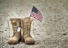Trusted Insider Drains Disabled Vets’ Cash Combat boots with dog tags and a small American flag on gravel