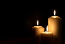 Three lit candles against a dark background