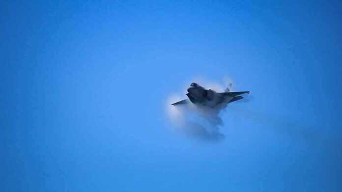 fighter jet creating vapor cone in blue sky