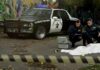 City Employee Linked To Cop Ambush Crime scene with police car and two investigators by a covered body