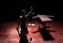 Execution Drama Returns To Texas Lady Justice statue with scales in dramatic light beside an empty gurney