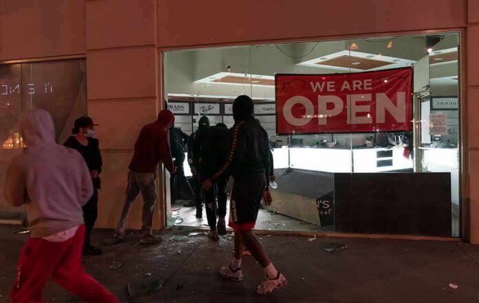 People outside a storefront with broken glass at night