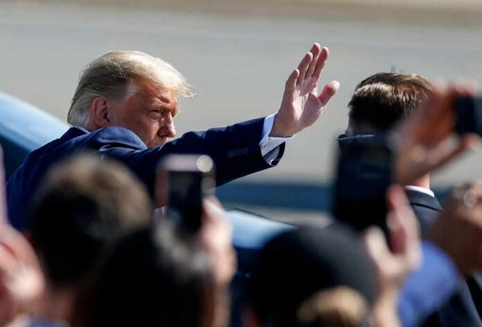 Donald Trump waves to a crowd while walking past onlookers