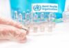 WHO Demands Receipts After Plague Scare Gloved hands holding vaccine vial and syringe near WHO banner