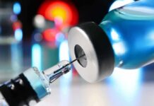 Syringe needle entering a vaccine vial