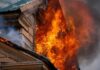 Evacuations Race Ahead of Firestorm House on fire with flames pouring from a window