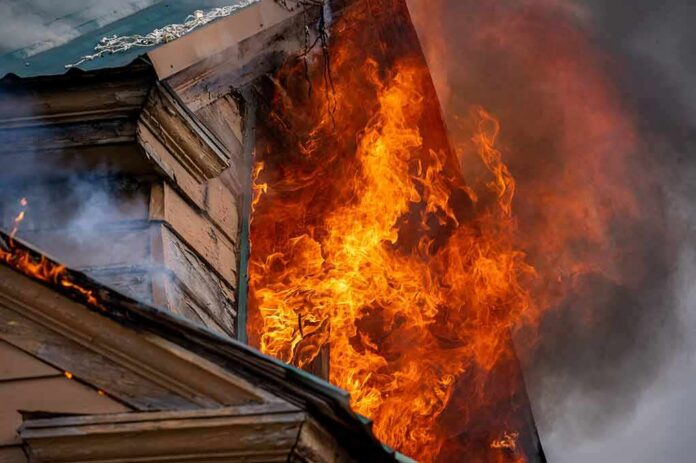 shutterstock_2129237024 House on fire with flames pouring from a window