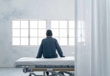 Person sitting on a hospital bed facing bright windows