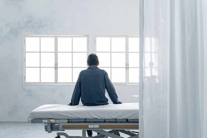 Person sitting on a hospital bed facing bright windows