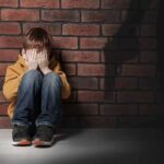 New Footage Reopens Questions In School Shooting boy sitting against brick wall covering his face