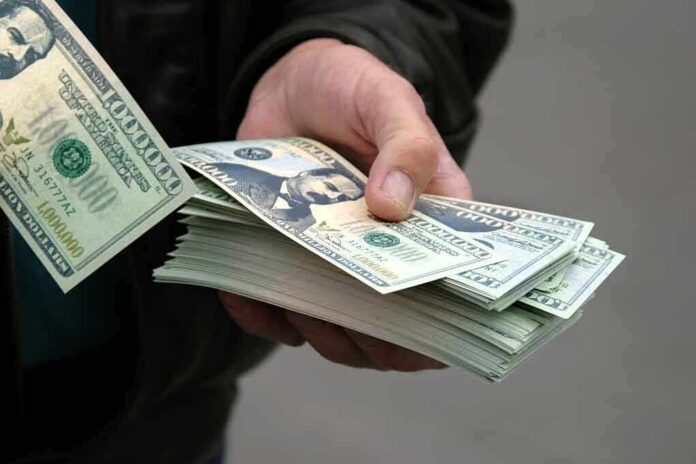 shutterstock_2908150 A hand holding a stack of hundred dollar bills with one bill prominently displayed