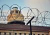 Barbed wire fence in front of a prison watchtower