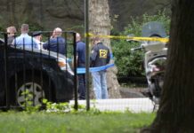 law enforcement officers gather at taped-off outdoor scene