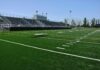 Empty football stadium with bleachers and artificial turf field