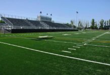 Empty football stadium with bleachers and artificial turf field