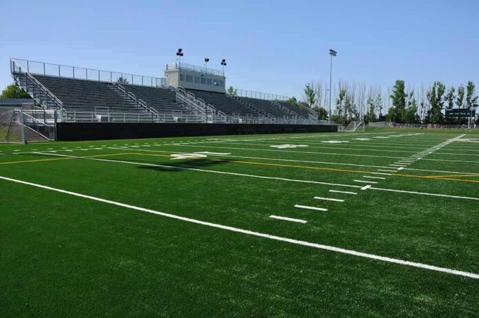 shutterstock_55132081 Empty football stadium with bleachers and artificial turf field