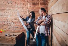 Taxes And Insurance Ambush Homeowners Two people reviewing blueprints in a rustic room under renovation
