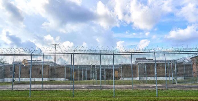 shutterstock_732521716-1 Prison yard behind chain-link and razor wire fence